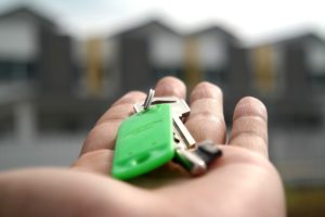 close up of hand holding keys facing new home