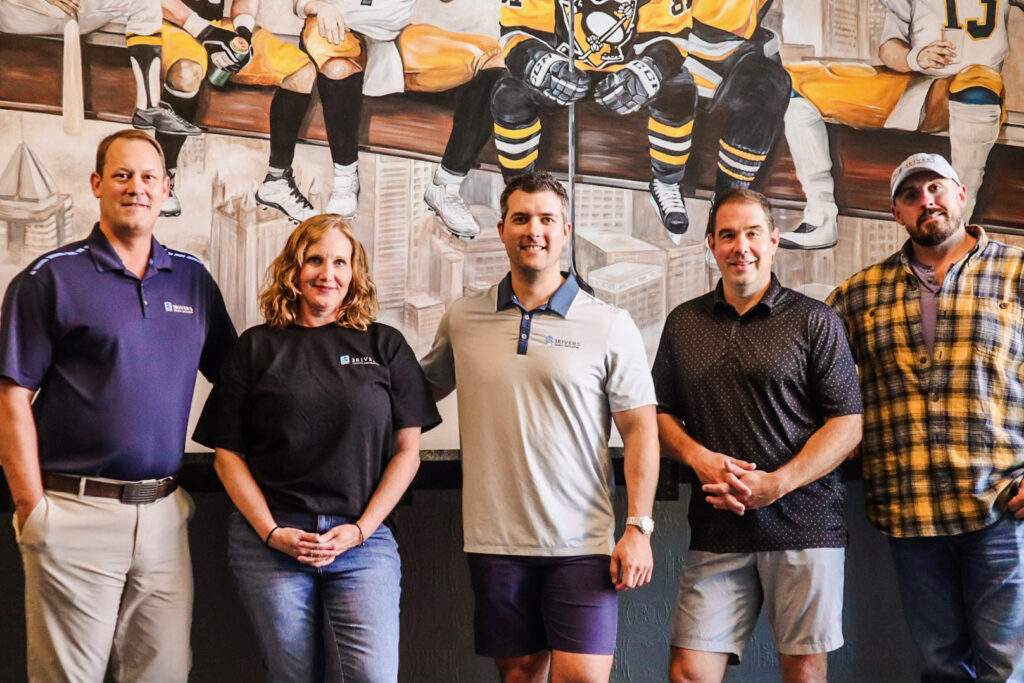 Group of people standing in front of Pittsburgh Penguins mural.