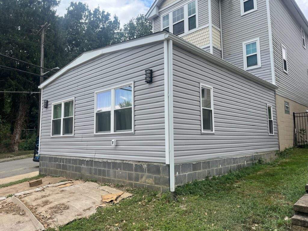 Gray vinyl siding on a house addition with block foundation.