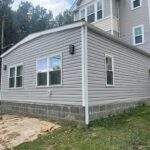 Gray vinyl siding on a house addition with block foundation.