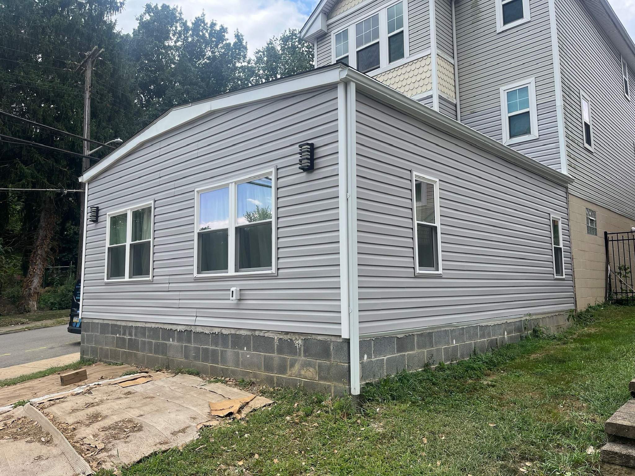 Gray vinyl siding on a house addition with block foundation.
