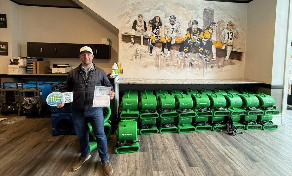Man with IICRC certification, water damage restoration equipment, and Steelers mural.