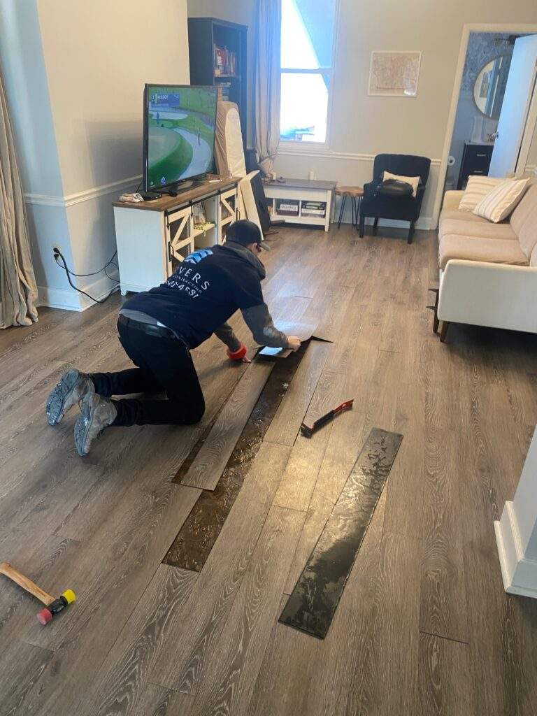 Man installing new wood-look flooring in a living room.