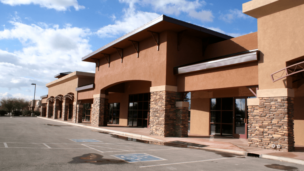 Empty parking lot with beige storefronts and brick pillars