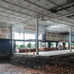 Interior of a building under construction with exposed beams and large windows