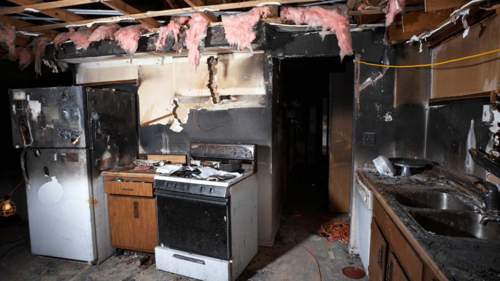 Kitchen with fire damage, burnt appliances, and smoke-stained walls