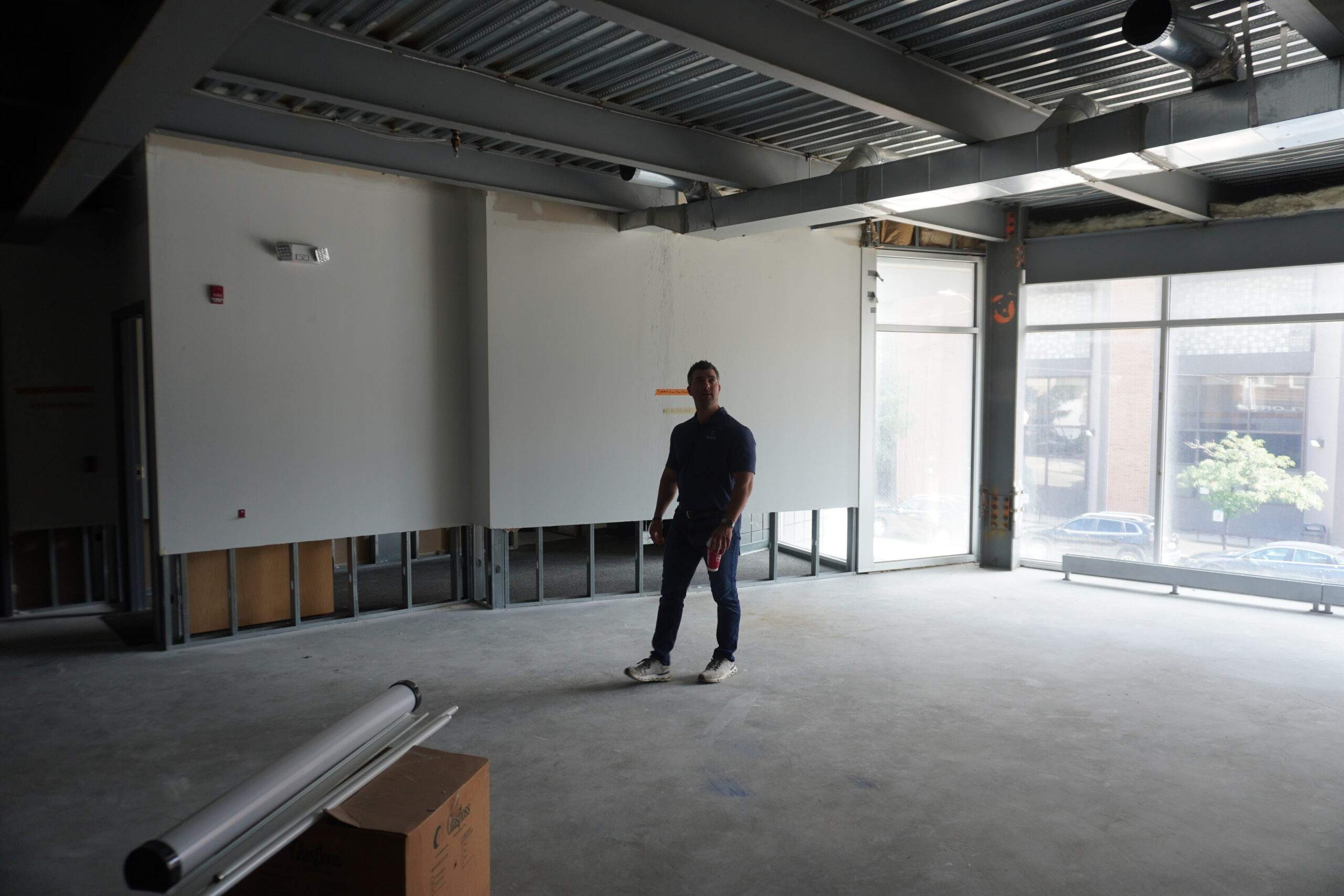 Man standing in unfinished commercial space with exposed beams and windows