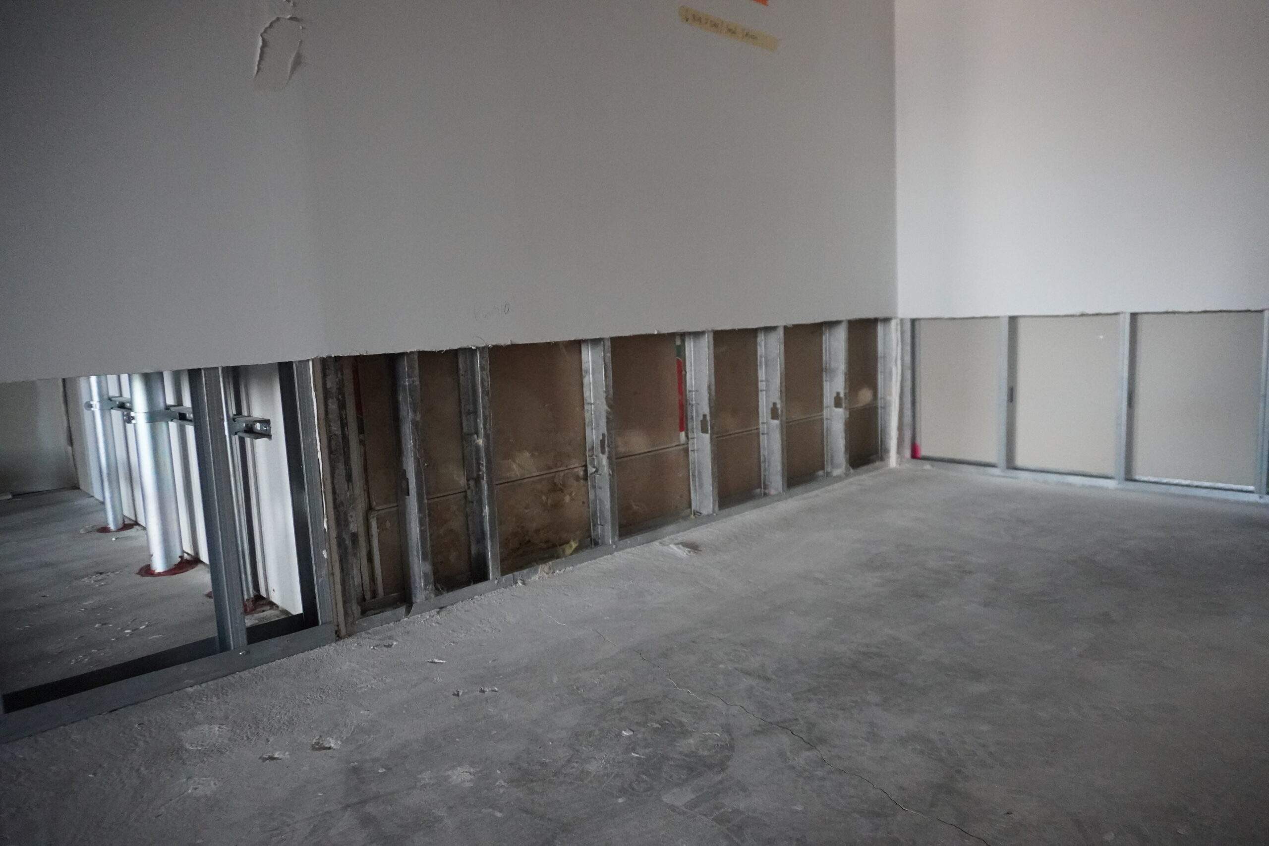 Interior wall demolition exposing metal studs and concrete floor