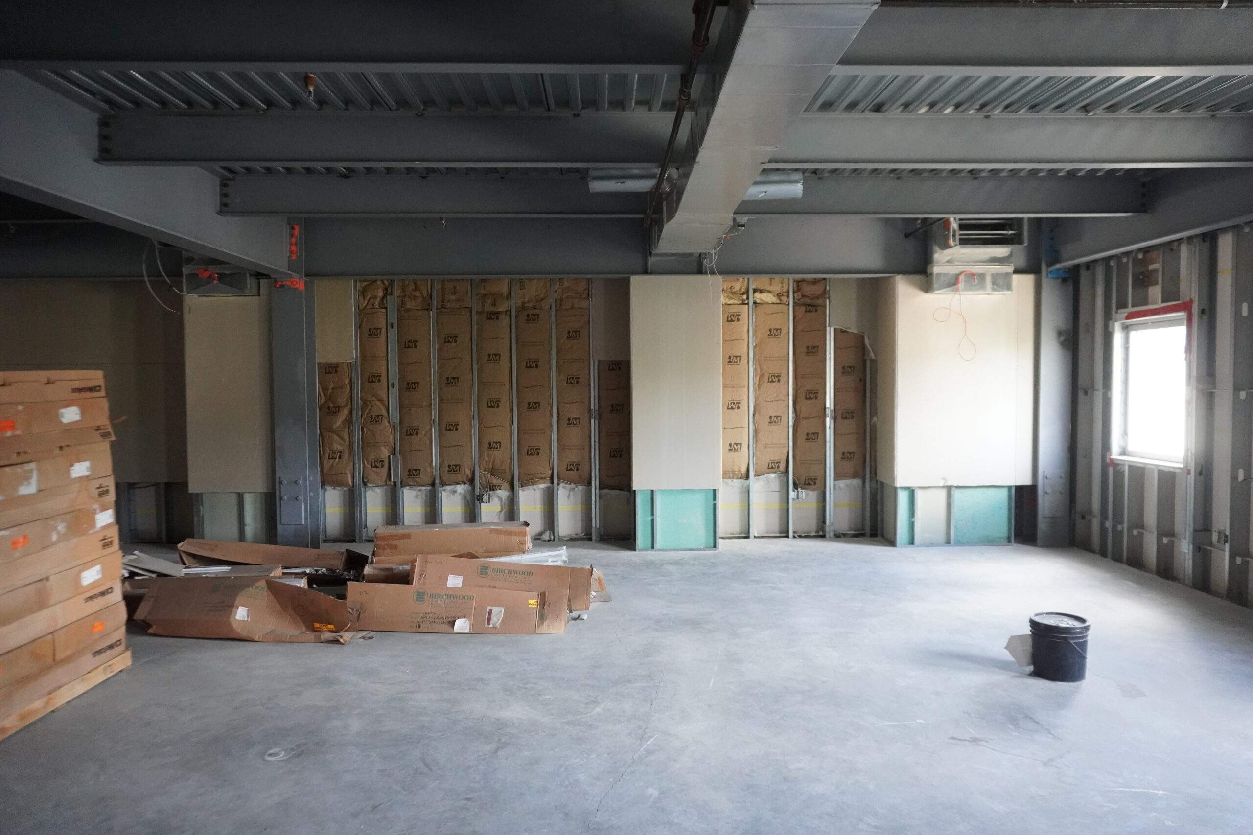 Construction site interior with exposed framing, insulation, and building materials