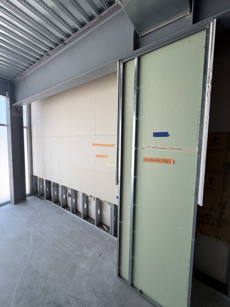 Construction site with drywall, metal framing, and insulation visible.