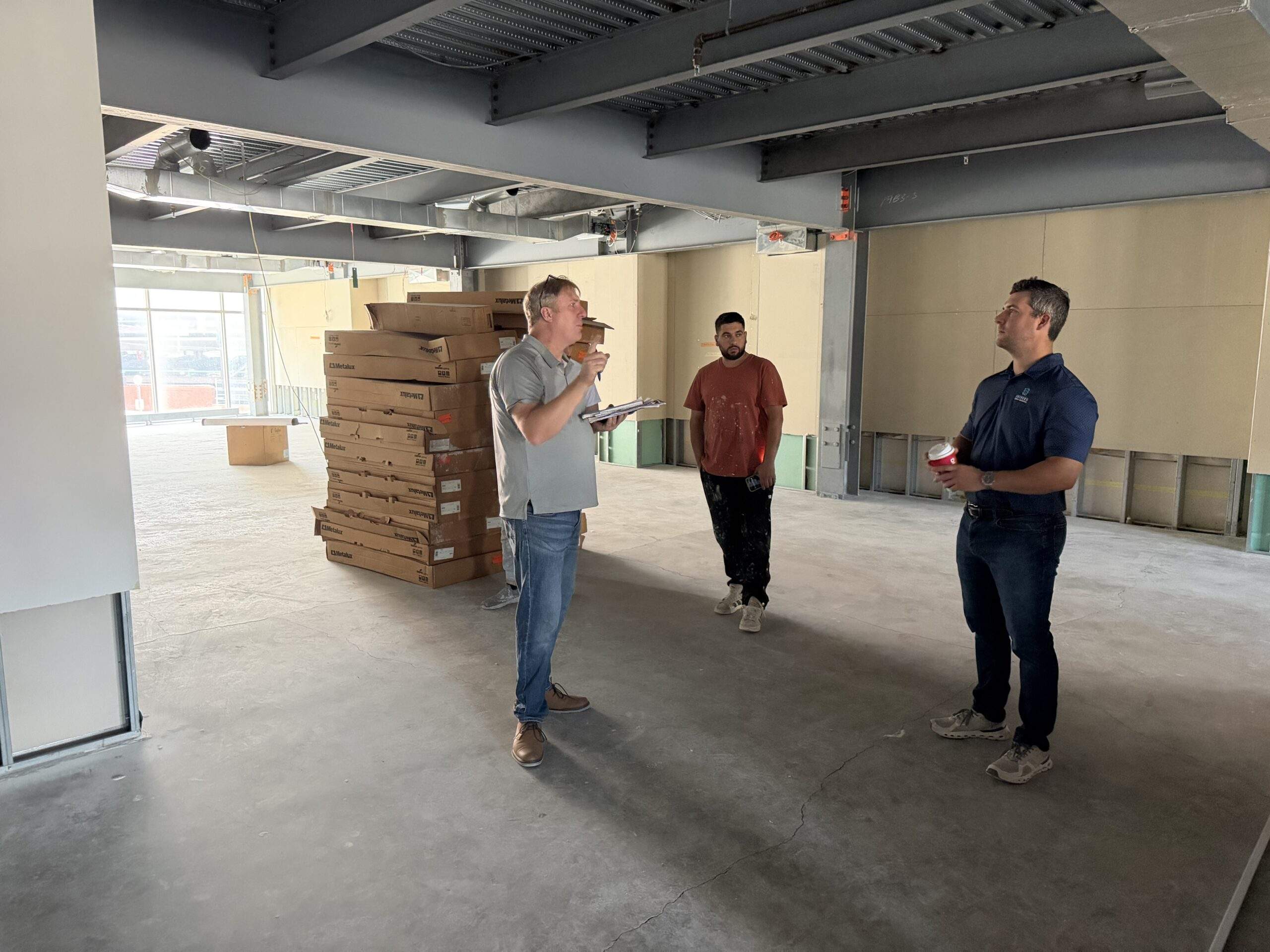 Construction workers in an unfinished room discuss plans.