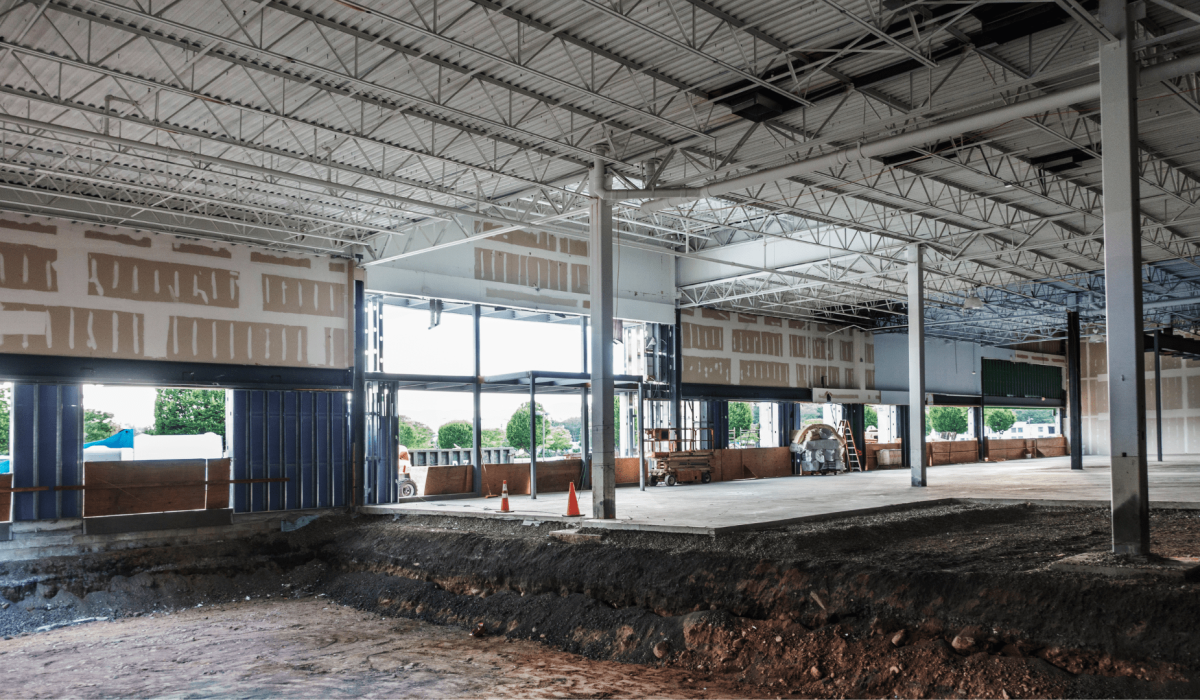 Interior of a building under construction with exposed beams and large windows
